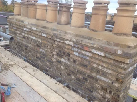 Rebuilt brick chimney stack with pale coping and terracotta chimney pots.