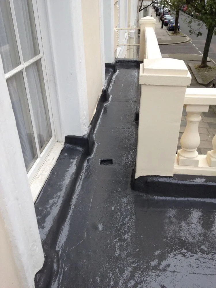 Narrow dark roof surface beside a white exterior wall and window openings.