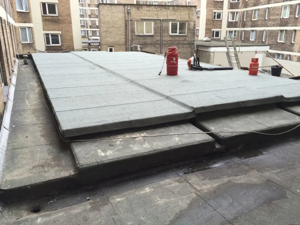 Raised flat-roof platform with pale panels in a courtyard between buildings.