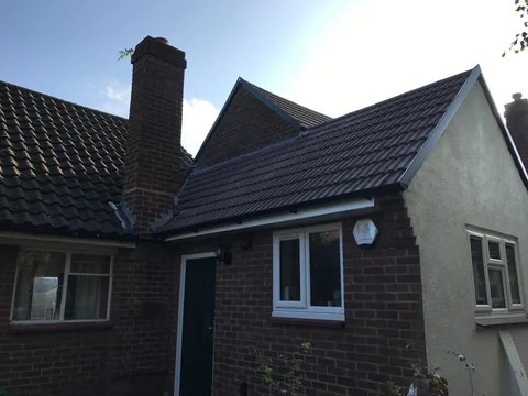 House with a dark tiled pitched roof and prominent chimney.
