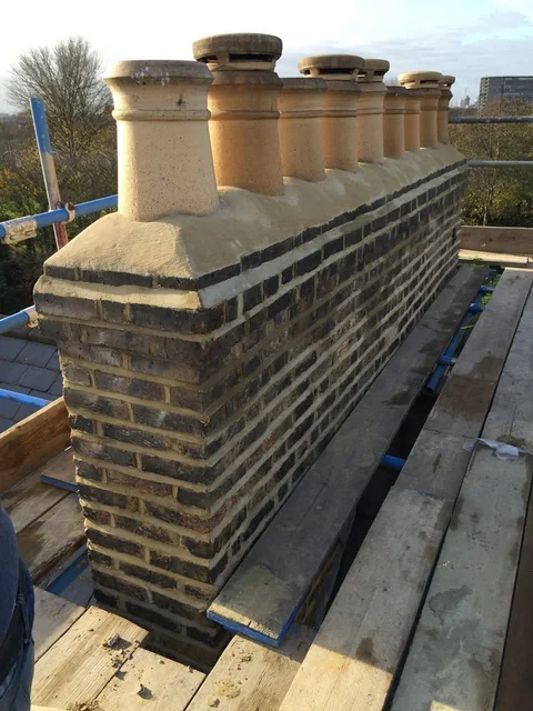 Rebuilt brick chimney stack with pale coping and terracotta chimney pots.