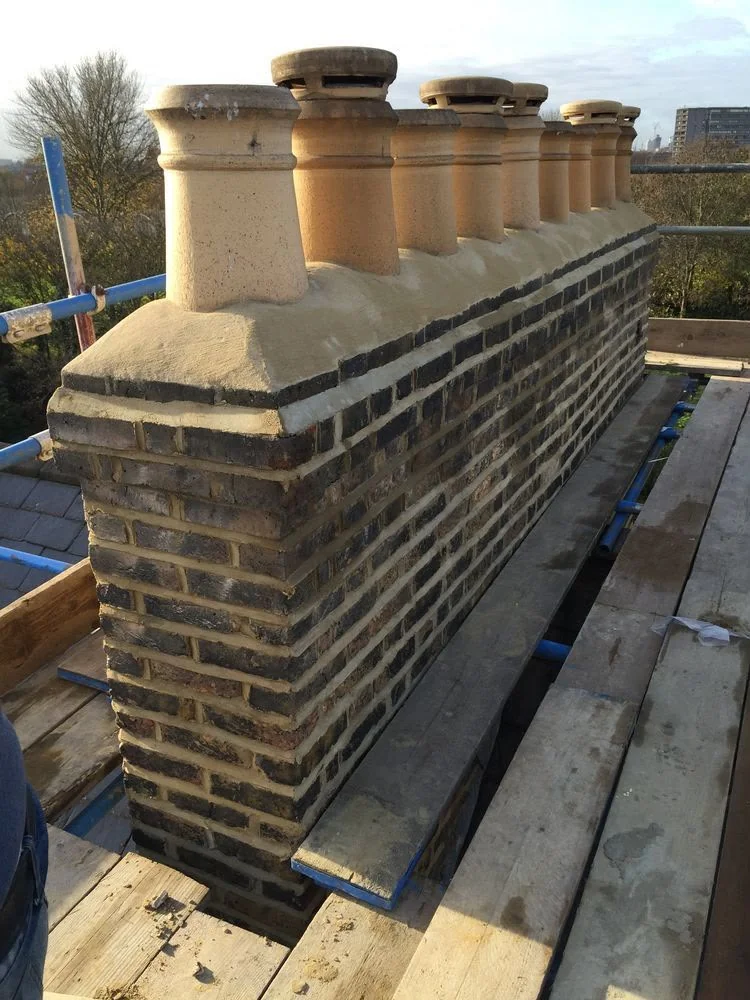 Rebuilt brick chimney stack with pale coping and terracotta chimney pots.