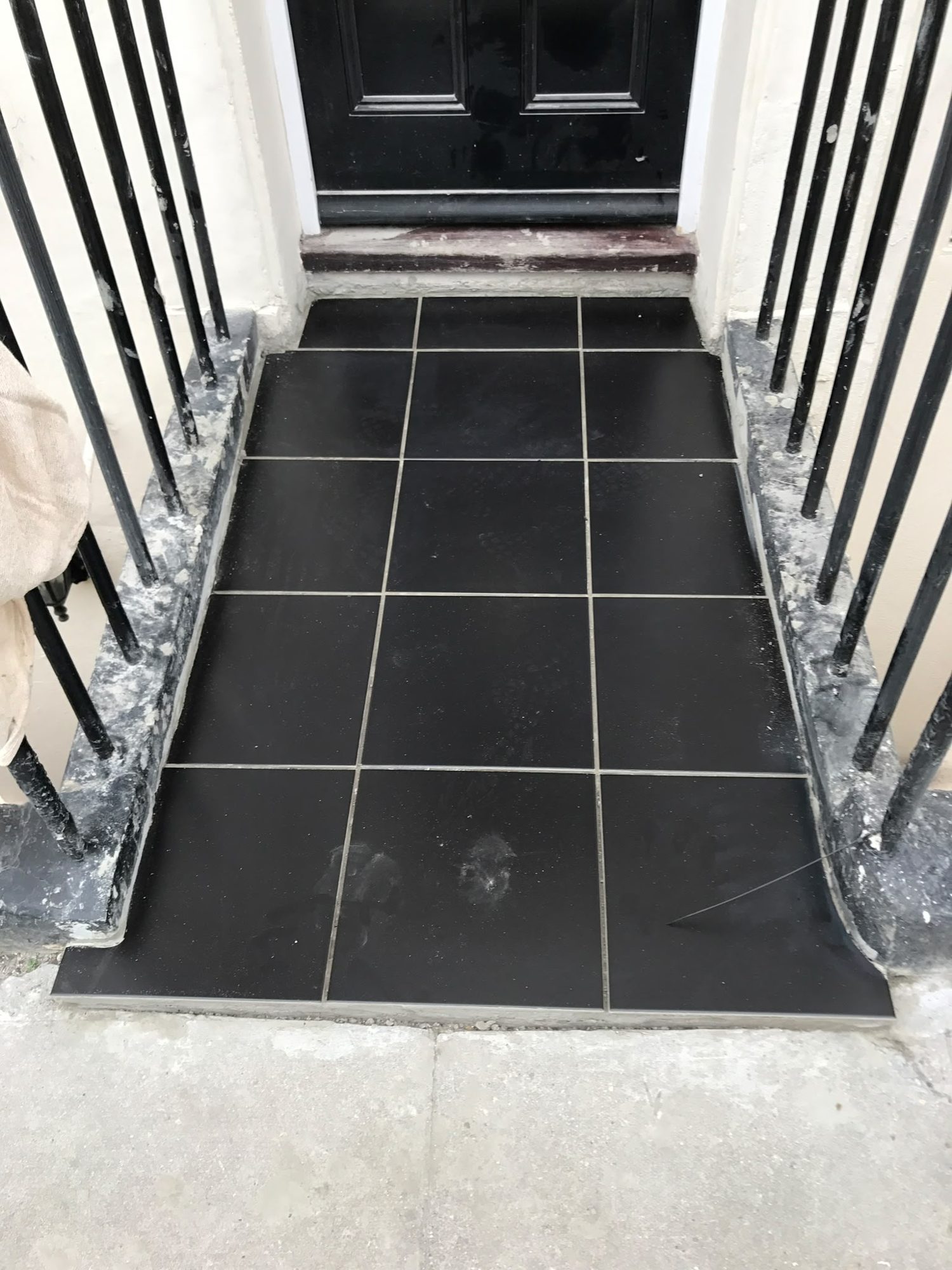 Black entrance tiles bordered by metal railings