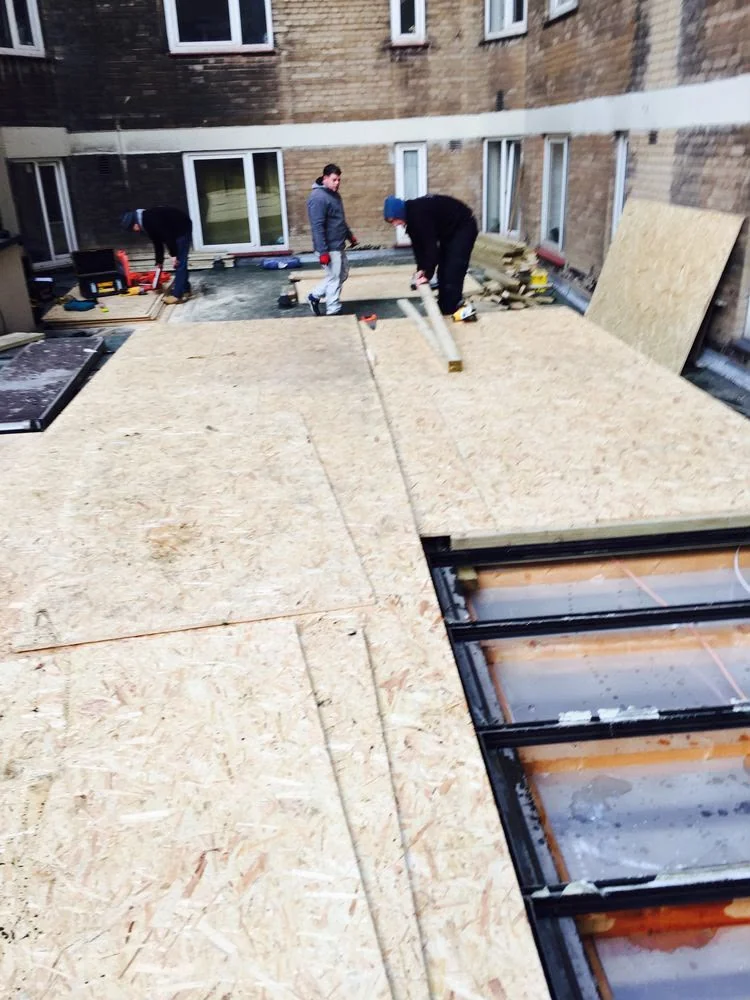 Plywood roof decking beside glazed roof panels in a courtyard.