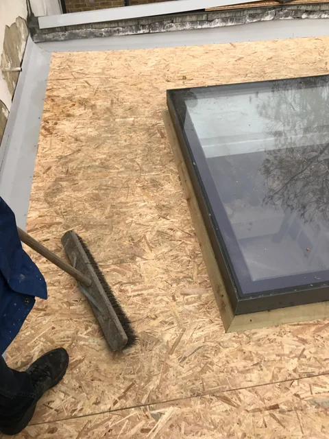 Prepared flat-roof plywood decking around a rectangular rooflight.